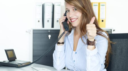 Business woman having a good call at work and shows thumb up
